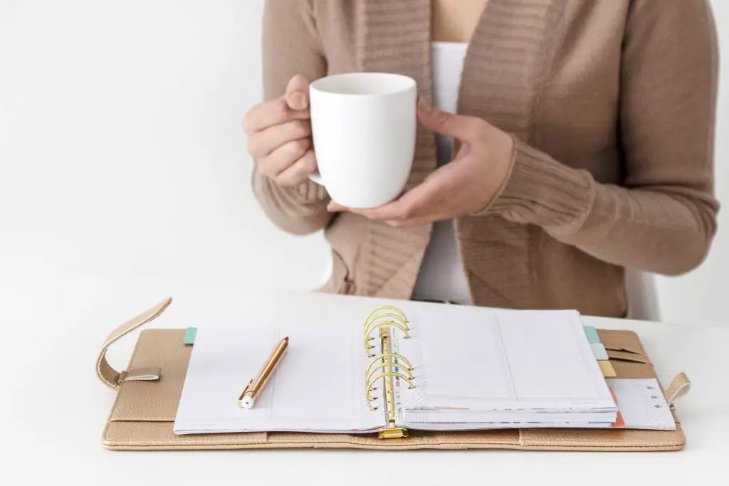 Woman drinking coffee with clipboard