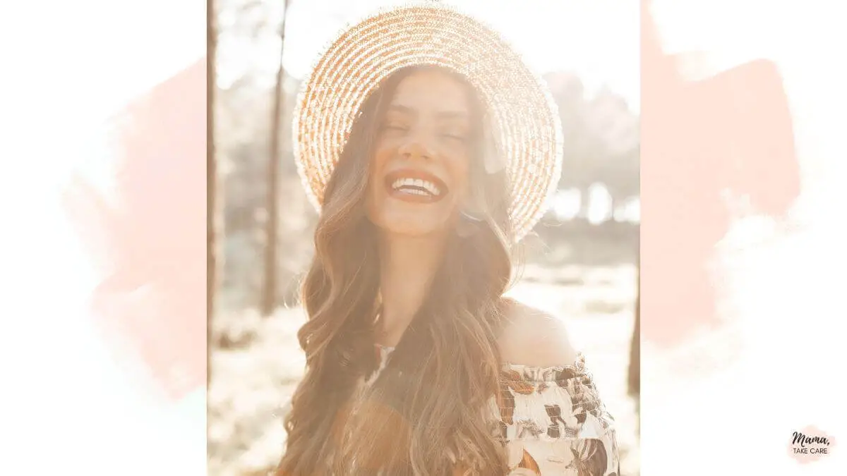 Woman wearing a hat, laughing, pink white background