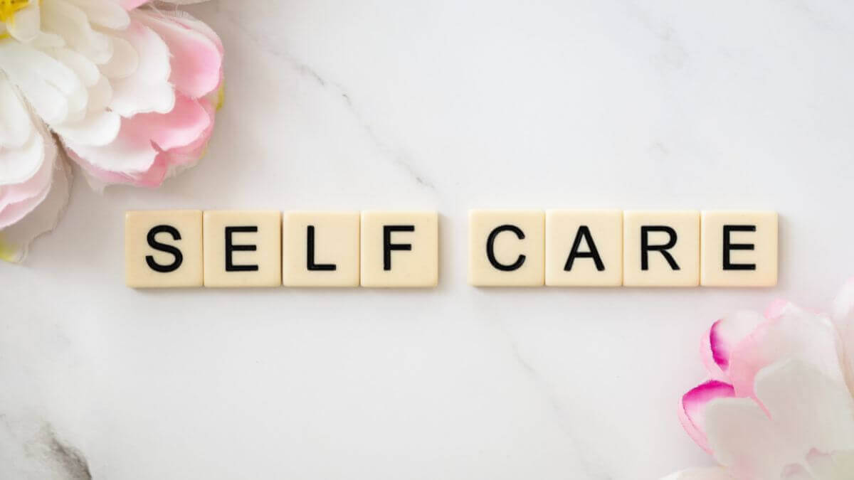 tiles spelling "self-care" pink flowers: Self-care for Moms